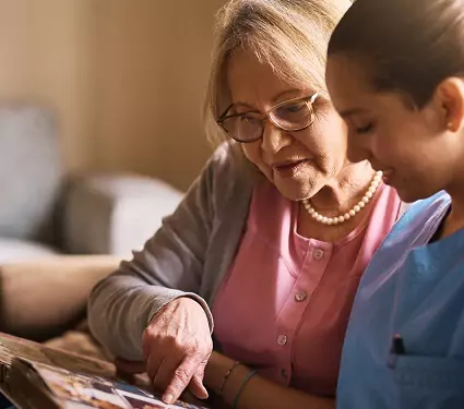 caregiver and senior lady looking at pictures